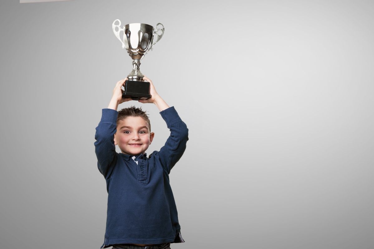 A school boy holding an end-of-year award.